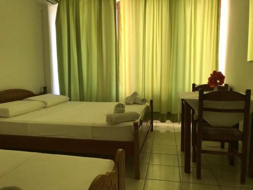 a bedroom with two beds and a table and a chair at Hotel Tatzati in Sarandë