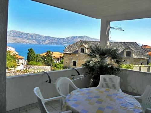 a table and chairs on a balcony with a view of the water at Apartment Katija in Postira