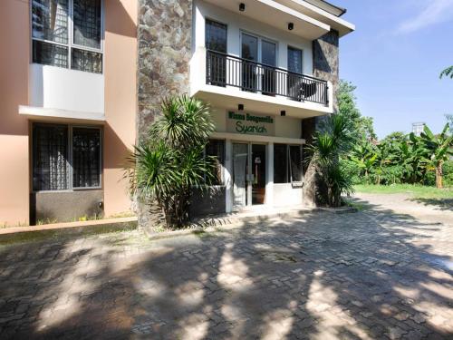 a building with palm trees in front of it at RedDoorz Syariah Plus @ Wisma Bougenville Karawaci in Tangerang