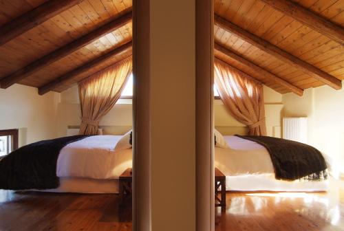 two beds in a bedroom with wooden ceilings at Monte Bianco Villas in Arachova