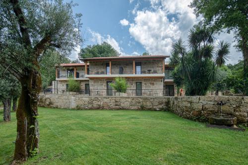 a large house with a stone wall and a yard at Casa do Rio in Mondim de Basto