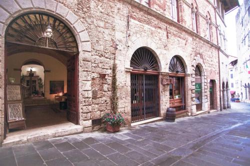 an empty street with a brick building with a gate at Residenza d'Epoca Palazzo Malfatti in Massa Marittima