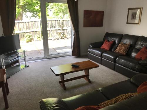 a living room with a black leather couch and a coffee table at The Number Eleven Apartment in Kilmuir