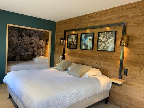 Lanarceにあるhotel des Sapinsのベッドルーム1室(ベッド2台付)が備わります。壁に2枚の写真が飾られています。
