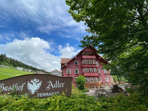 - un grand bâtiment rouge avec un panneau devant dans l'établissement Gasthof Adler, à Doren