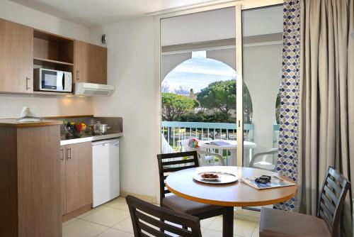 a kitchen and dining room with a table and a window at Residence Residéal La Grande Motte in La Grande-Motte