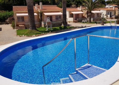 a large blue swimming pool with stairs in front of a house at Beach Resort La Margarita in Hospitalet de l'Infant