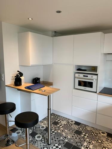 une cuisine avec des placards blancs, une table et des tabourets dans l'établissement Splendide appartement proche de tous commodités, à Le Touquet-Paris-Plage