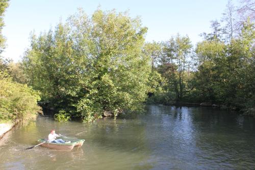 a man is rowing a boat on a river at Cottage d'Exception - Coeur de Normandie in Vienne-en-Bessin