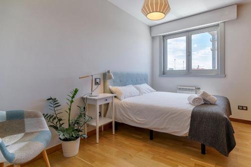 a bedroom with a bed and a chair and a window at Blue Ocean Penthouse in A Coruña