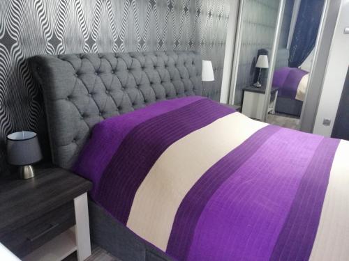 a bedroom with a purple and white bed and a table at Apartament Nadmorski in Kołobrzeg