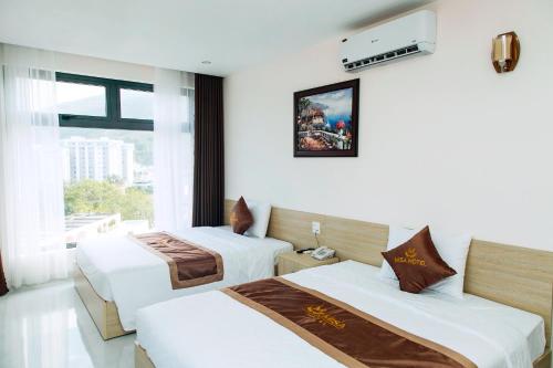 a hotel room with two beds and a window at Khách sạn Misa in Quy Nhon