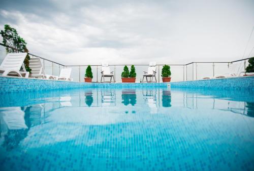 a swimming pool with white chairs and blue water at Holiday Apartment 7 in Hisarya