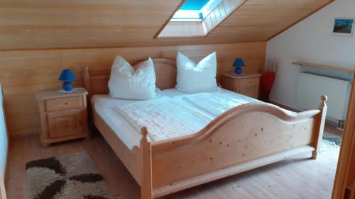 een slaapkamer met een houten bed met witte kussens bij Ferienwohnung Brigitte in Schernfeld