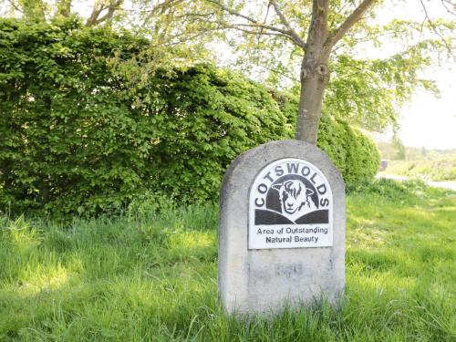 a stone sign in the grass next to a tree at Goose Lodge in Shipston on Stour