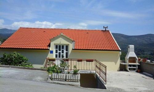 een klein huis met een oranje dak en een balkon bij Apartments Mara in Molunat