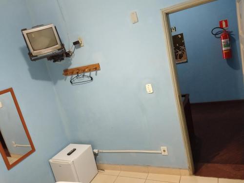 a bathroom with a tv on the wall next to a toilet at Hotel Paulista in São Vicente