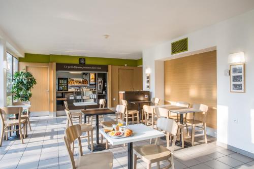 a restaurant with tables and chairs and a counter at B&B HOTEL Freyming-Merlebach in Freyming