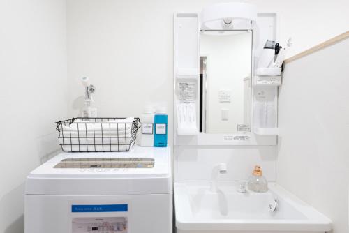 a white kitchen with a sink and a mirror at Raku in Fujisawa