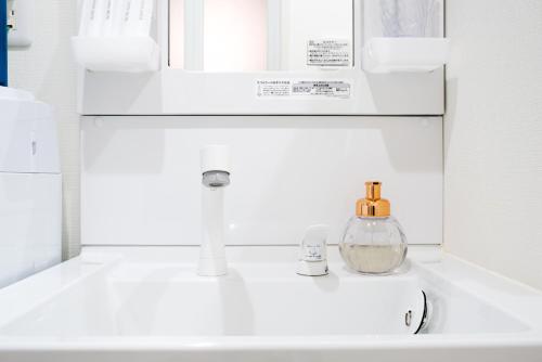 a bathroom sink with a bottle of perfume on it at Raku in Fujisawa