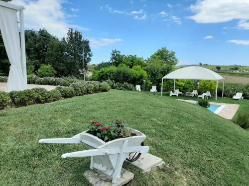 a white bench with flowers on the grass at I Tre Laghi Countryhouse 14 posti letti Cottage 10 posti letti in Citta' Sant'Angelo