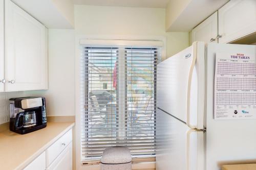a kitchen with a refrigerator and a window with blinds at Spinnaker 753 in Seabrook Island