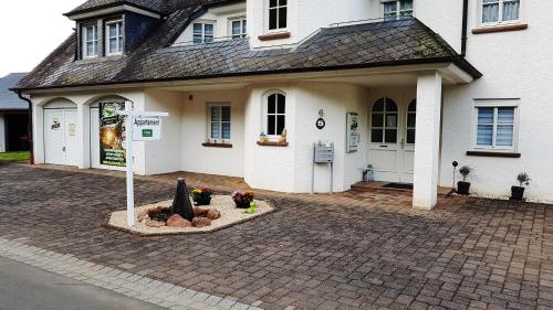a white house with a sign in front of it at Zimmerappartement "Rose" - Ferienwohnungen Wagner & Gaul in Falkenauel