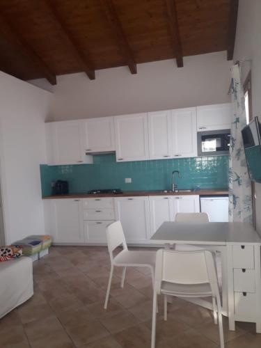 a kitchen with white cabinets and a table and chairs at Magnolia Rooms in Civitavecchia