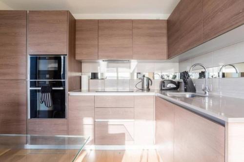 a kitchen with wooden cabinets and stainless steel appliances at Luxury river side penthouse in London