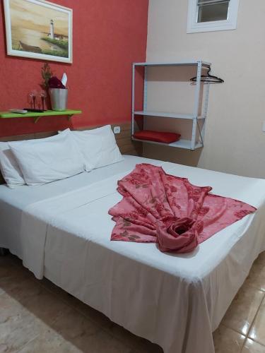 Una cama con un vestido rosa encima. en Residencial Luanda, en Porto Seguro