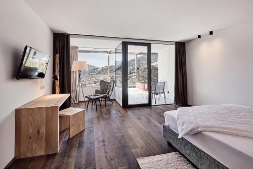 a bedroom with a bed and a desk and a balcony at Haller Suites & Restaurant in Bressanone
