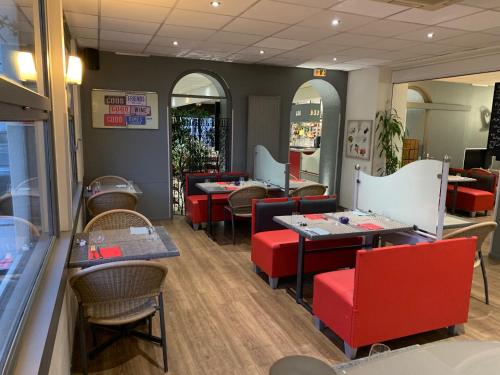 a restaurant with tables and red chairs and a counter at Hotel les Commercants in Clermont-Ferrand