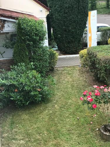 a yard with some pink flowers and bushes at Première Classe Metz Nord - Talange in Talange