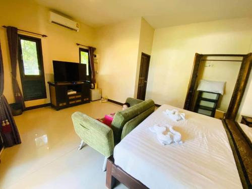 a living room with a large white bed and chairs at Saphli Villa in Chumphon
