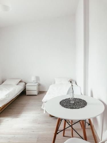 a white room with a table and two beds at Przytulny domek in Mielno