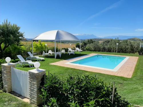 einen Pool in einem Garten mit Stühlen und einem Sonnenschirm in der Unterkunft Rustic Home with pool in Città Sant'Angelo