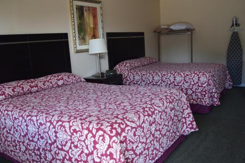 two beds in a hotel room with red sheets at The Cullars Inn in Lincolnton