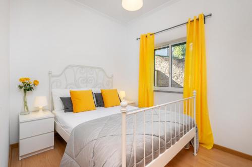 a bedroom with a bed with yellow curtains and a window at Casa da Oliveira, Aradas, Pampilhosa da Serra, Wifi, Ar Condicionado, Churrasqueira, Parqueamento, by IG in Unhais-o-Velho