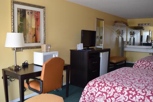 a hotel room with a bed and a desk with a computer at The Cullars Inn in Lincolnton