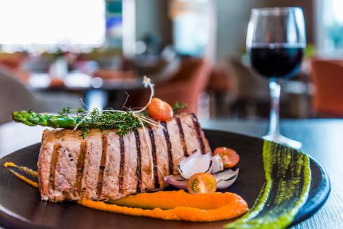 a piece of meat on a plate with a glass of wine at Holiday Inn Cúcuta by IHG in Cúcuta