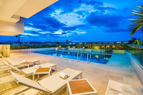 a pool on the roof of a building with tables and chairs at Holiday Inn Cúcuta by IHG in Cúcuta