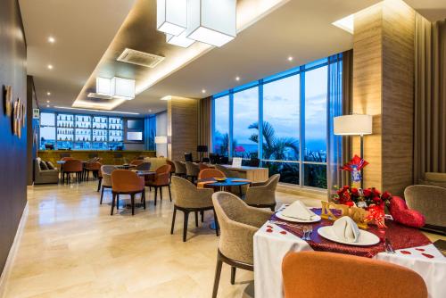 un restaurante con mesas, sillas y ventanas grandes en Holiday Inn Cúcuta, an IHG Hotel en Cúcuta