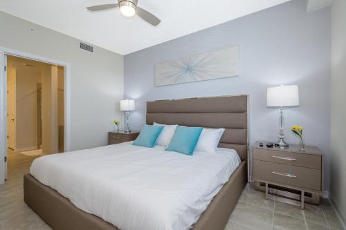a bedroom with a large white bed with blue pillows at (JA206) Storey Lake Condo 2/2, Free Waterpark in Kissimmee