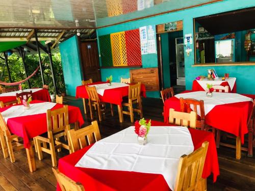 Un restaurante con mesas y sillas rojas y blancas. en All Rankins Eco-Lodge, en Tortuguero