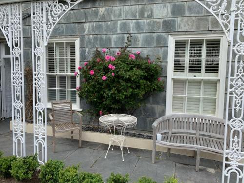 un patio con 2 sillas, una mesa y un arbusto con flores rosas en Coswarth House en Padstow