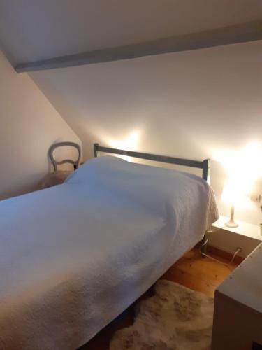a white bed in a room with a lamp at La Maisonnette in Wissant