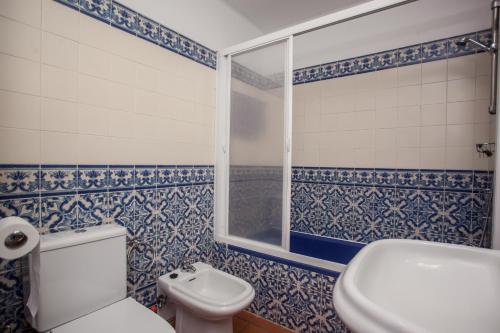 a bathroom with blue and white tiled walls and a toilet at Apartamento Charmoso no Funchal, com grande Jardim e Vista Esplêndida in Funchal