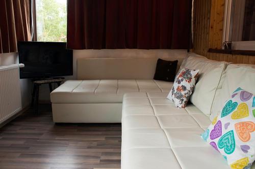 ein weißes Sofa im Wohnzimmer mit TV in der Unterkunft Apartament Mountain Life in Buşteni
