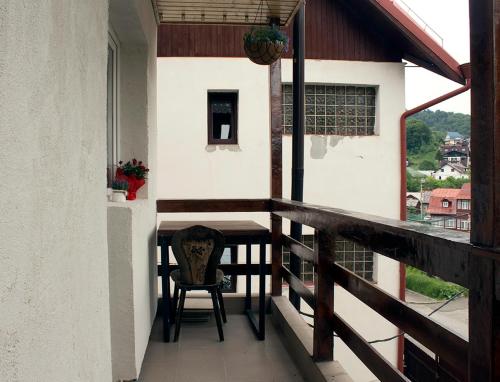 einen Balkon eines Hauses mit einem Tisch und einem Stuhl in der Unterkunft Apartament Mountain Life in Buşteni