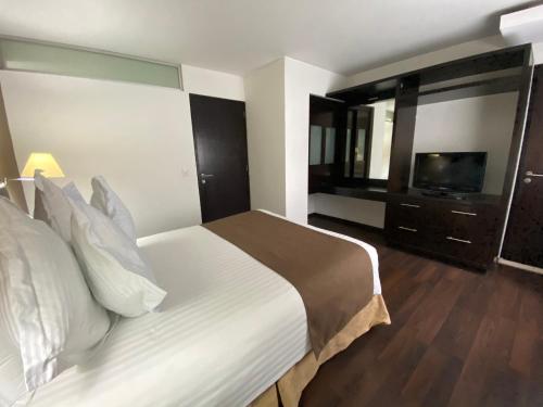a hotel room with a bed and a television at Suites Teca Once in Mexico City